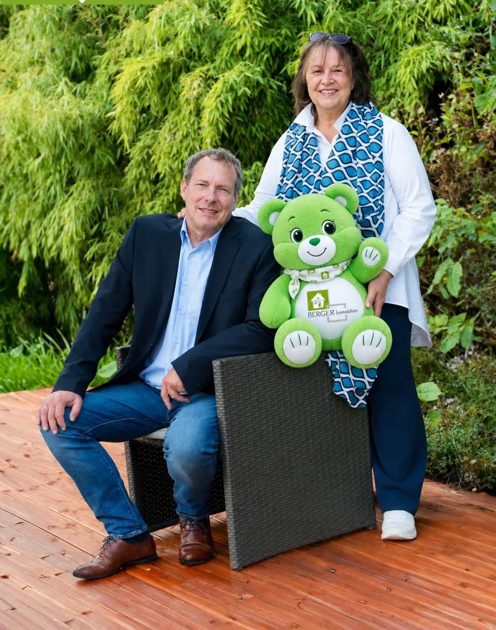 Gabi und Detlev Berger auf einer Bank im Garten, Detlev hält den grünen BERGER Bär