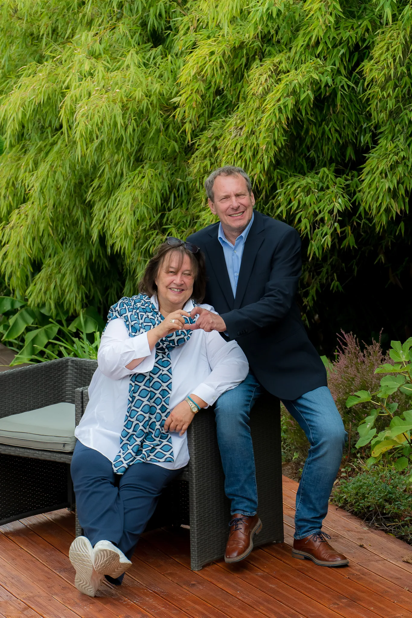 Gabi und Detlev Berger im Garten, sie formen mit den Händen ein Herz