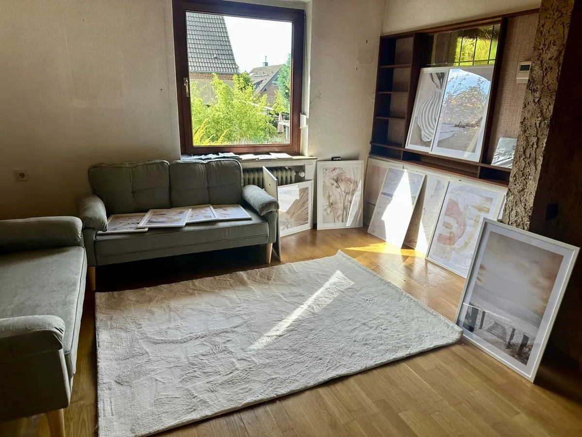 Wohnzimmer mitten in der Vorbereitung: Sofa, leere Regale und Bilderrahmen, die an der Wand lehnen
